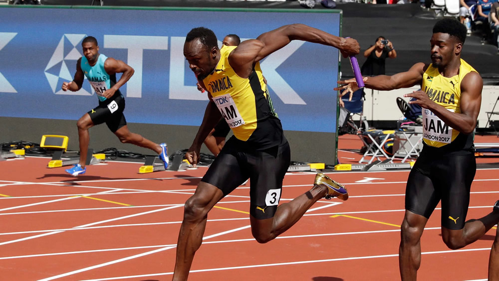 Usain Bolt v plnej rýchlosti preberá štafetu vo finálovom behu 4x100m na MS 2017 v atletike